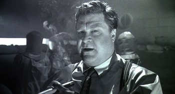 Movie still from “Matinee” (1993), directed by Joe Dante – A black and white photo of a man smoking a cigarette; Close Up shot, Low angle