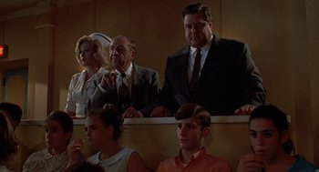 Movie still from “Matinee” (1993), directed by Joe Dante – A group of people sitting in a row of seats; Medium shot, Low angle