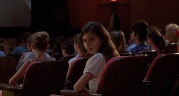 Movie still from “Matinee” (1993), directed by Joe Dante – A woman sitting in a row of seats in front of a group of people; Medium shot, High angle