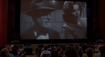 Movie still from “Matinee” (1993), directed by Joe Dante – A large group of people sitting in front of a projector screen; Wide shot, Over the shoulder angle