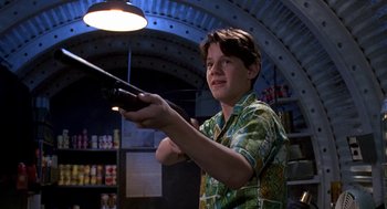 Movie still from “Matinee” (1993), directed by Joe Dante – A young man holding a remote control in a room; Medium shot, Low angle