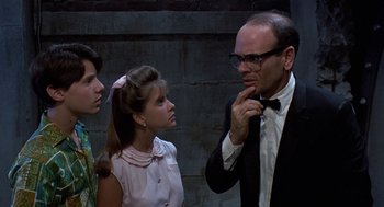 Movie still from “Matinee” (1993), directed by Joe Dante – A group of people standing next to each other in front of a brick wall; Medium shot, Over the shoulder angle