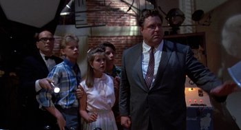 Movie still from “Matinee” (1993), directed by Joe Dante – A group of people standing next to each other in a room; Medium shot, Over the shoulder angle