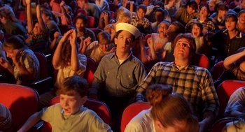 Movie still from “Matinee” (1993), directed by Joe Dante – A crowd of people sitting in seats watching a show; Medium shot, High angle