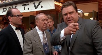 Movie still from “Matinee” (1993), directed by Joe Dante – Two men in suits and ties standing next to each other; Medium shot, Over the shoulder angle