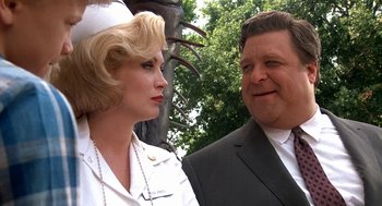 Movie still from “Matinee” (1993), directed by Joe Dante – A man and a woman standing next to each other in front of trees; Close Up shot, Low angle