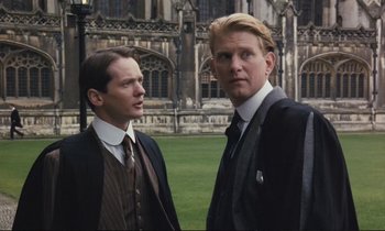 Movie still from “Maurice” (1987), directed by James Ivory – A couple of men standing next to each other on top of a field; Medium shot, Low angle
