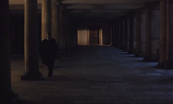 Movie still from “Maurice” (1987), directed by James Ivory – A man in a black coat walking down a street; Extreme Wide shot, High angle