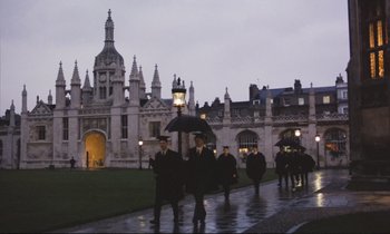 Movie still from “Maurice” (1987), directed by James Ivory – A group of people walking in the rain with an umbrella; Extreme Wide shot, High angle