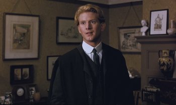 Movie still from “Maurice” (1987), directed by James Ivory – A man with blonde hair wearing a suit and tie; Close Up shot, Over the shoulder angle