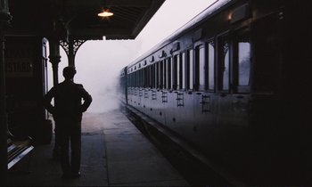 Movie still from “Maurice” (1987), directed by James Ivory – A man standing in front of a train on a train platform; Wide shot, Low angle