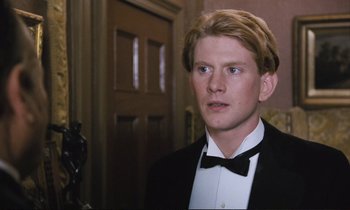 Movie still from “Maurice” (1987), directed by James Ivory – A man in a tuxedo standing in front of a door; Close Up shot, High angle