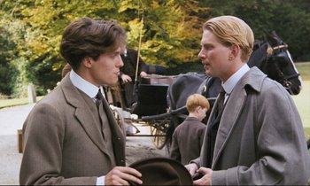 Movie still from “Maurice” (1987), directed by James Ivory – Two men in suits talking to each other outside; Medium shot, Over the shoulder angle