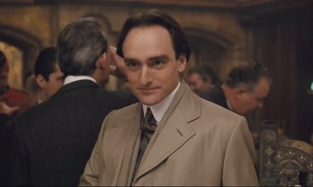 Movie still from “Maurice” (1987), directed by James Ivory – A man in a suit and tie standing in front of a crowd; Close Up shot, Low angle