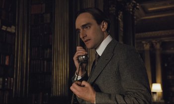 Movie still from “Maurice” (1987), directed by James Ivory – A man talking on a phone while wearing a suit and tie; Close Up shot, Low angle