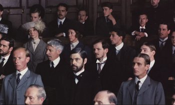 Movie still from “Maurice” (1987), directed by James Ivory – A group of men in suits and ties sitting in a courtroom; Medium shot, High angle