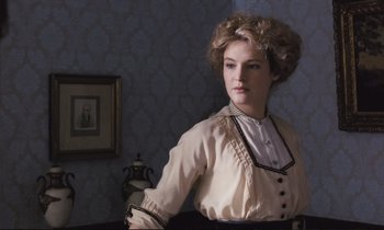 Movie still from “Maurice” (1987), directed by James Ivory – A woman standing in front of a wall with a picture on the wall; Medium shot, Low angle