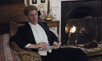 Movie still from “Maurice” (1987), directed by James Ivory – A man in a tuxedo sitting in front of a fireplace; Medium shot, High angle