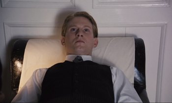 Movie still from “Maurice” (1987), directed by James Ivory – A man in a vest and tie laying on a bed; Medium shot, High angle