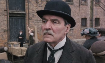 Movie still from “Maurice” (1987), directed by James Ivory – An older man in a suit and a black hat; Close Up shot, Low angle