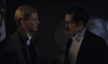 Movie still from “Maurice” (1987), directed by James Ivory – A man and a woman standing next to each other in a dark room; Close Up shot, Over the shoulder angle