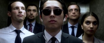 Movie still from “Mayhem” (2017), directed by Joe Lynch – A man in a suit and sunglasses with two other men in suits; Close Up shot, Low angle