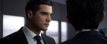 Movie still from “Mayhem” (2017), directed by Joe Lynch – A man wearing a suit and tie talking to another man wearing a suit and tie; Close Up shot, Over the shoulder angle