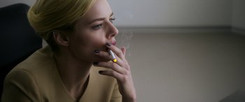 Movie still from “Mayhem” (2017), directed by Joe Lynch – A woman smoking a cigarette while looking at the camera; Close Up shot, Over the shoulder angle