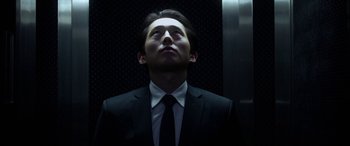 Movie still from “Mayhem” (2017), directed by Joe Lynch – A man wearing a suit and tie standing in front of an elevator; Close Up shot, Low angle