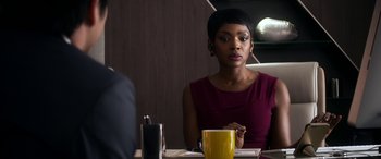 Movie still from “Mayhem” (2017), directed by Joe Lynch – A woman sitting at a table in front of a yellow cup; Close Up shot, Over the shoulder angle