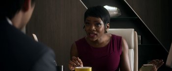 Movie still from “Mayhem” (2017), directed by Joe Lynch – A woman sitting at a table with a drink in front of her; Close Up shot, Over the shoulder angle