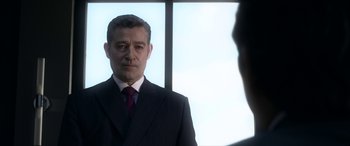 Movie still from “Mayhem” (2017), directed by Joe Lynch – A man wearing a suit and tie standing in front of a window; Close Up shot, Over the shoulder angle
