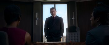 Movie still from “Mayhem” (2017), directed by Joe Lynch – A man in a suit standing in front of a window; Medium shot, Low angle