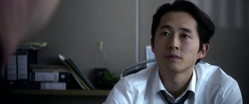 Movie still from “Mayhem” (2017), directed by Joe Lynch – A man in a white shirt and tie sitting in front of a computer; Close Up shot, Over the shoulder angle