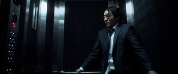 Movie still from “Mayhem” (2017), directed by Joe Lynch – A man wearing a suit and tie standing in an elevator; Medium shot, Low angle