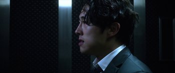 Movie still from “Mayhem” (2017), directed by Joe Lynch – A man wearing a suit and tie looking to the side; Close Up shot, Over the shoulder angle