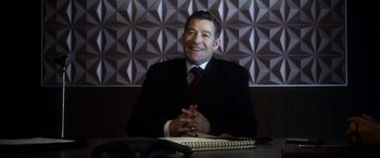 Movie still from “Mayhem” (2017), directed by Joe Lynch – A man sitting at a table in front of a phone; Medium shot, High angle