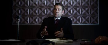 Movie still from “Mayhem” (2017), directed by Joe Lynch – A man sitting at a table in front of a phone; Medium shot, High angle