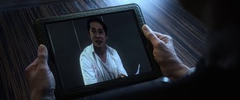 Movie still from “Mayhem” (2017), directed by Joe Lynch – A person holding a tablet in front of a man; Close Up shot, Over the shoulder angle