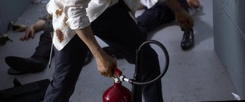 Movie still from “Mayhem” (2017), directed by Joe Lynch – A man holding a fire extinguisher while standing next to a hose; Extreme Close Up shot, High angle