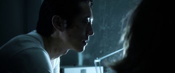 Movie still from “Mayhem” (2017), directed by Joe Lynch – A young man is smoking a cigarette in a dark room; Close Up shot, Over the shoulder angle