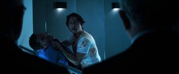 Movie still from “Mayhem” (2017), directed by Joe Lynch – A man in white shirt holding a steering wheel; Medium shot, Over the shoulder angle
