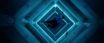 Movie still from “Mayhem” (2017), directed by Joe Lynch – A man standing in the middle of a room with blue lighting; Wide shot, Overhead angle