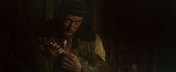 Movie still from “McCabe & Mrs. Miller” (1971), directed by Robert Altman – A man holding a violin in a dark room; Close Up shot, Low angle