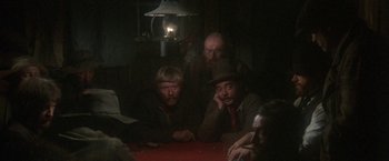Movie still from “McCabe & Mrs. Miller” (1971), directed by Robert Altman – A group of people sitting around a table; Medium shot, High angle