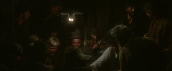 Movie still from “McCabe & Mrs. Miller” (1971), directed by Robert Altman – A group of men sitting around a table; Wide shot, High angle