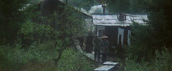 Movie still from “McCabe & Mrs. Miller” (1971), directed by Robert Altman – A group of people standing next to each other near trees; Extreme Wide shot, High angle