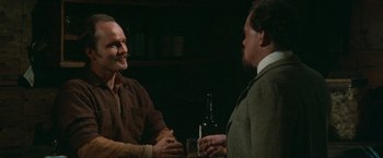 Movie still from “McCabe & Mrs. Miller” (1971), directed by Robert Altman – Two men are having a conversation at a bar; Medium shot, Over the shoulder angle