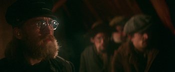 Movie still from “McCabe & Mrs. Miller” (1971), directed by Robert Altman – A group of men standing next to each other in the dark; Close Up shot, Over the shoulder angle