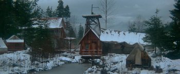 Movie still from “McCabe & Mrs. Miller” (1971), directed by Robert Altman – A wooden structure in the middle of a snow covered forest; Extreme Wide shot, High angle